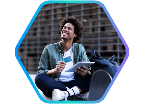 jovem moreno sentado em um ambiente externo, com skate e mochila, tablet e carto de crdito nas mos