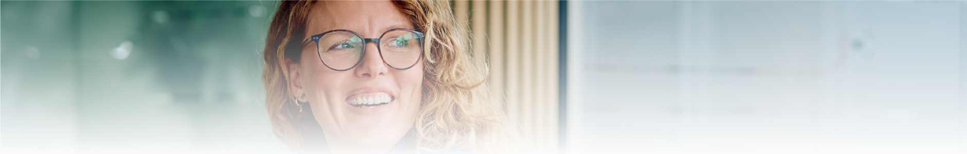 mulher de oculos e cabelos claros sorrindo em frente a notebook